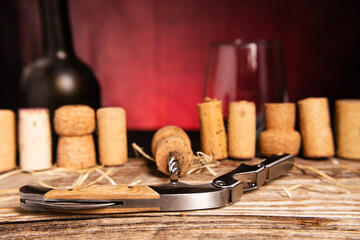 Sommelier knife and wine cork close-up on the background of used corks on a wooden table. Red...