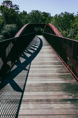 Wood and metal bridge in forest with shadows