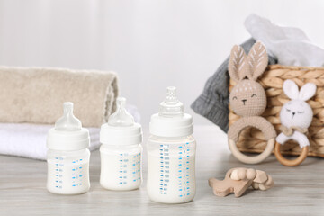 Feeding bottles with milk and baby accessories on white wooden table