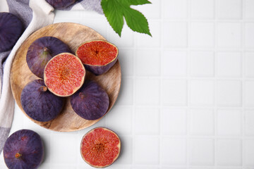 Fresh ripe purple figs on white tiled table, flat lay. Space for text