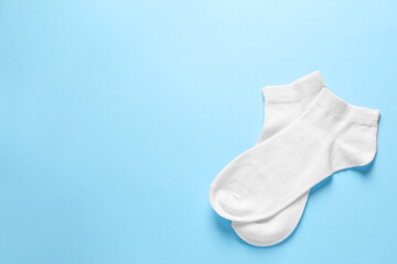 Pair of white socks on light blue background, flat lay. Space for text