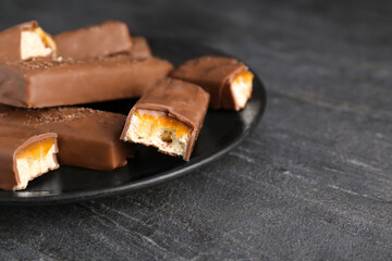 Plate with delicious chocolate bars on black table, closeup. Space for text