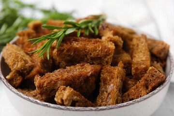 Delicious crispy rusks with rosemary in bowl, closeup view