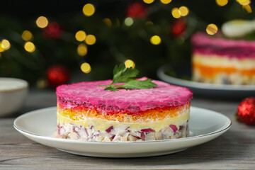 Herring under fur coat salad on white wooden table against blurred festive lights, closeup with space for text. Traditional Russian dish