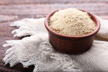 Brewer's yeast flakes in bowl on wooden table, closeup. Space for text