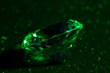 Beautiful dazzling diamond on green glitter surface, closeup