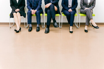 会社・オフィスで椅子に座るスーツ姿の会社員（アジア人・男女・5人）