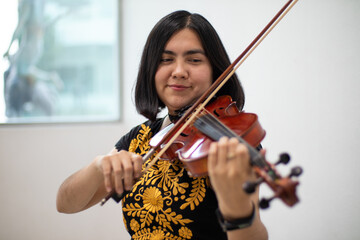 good looking hispanic violinist girl playing violin smiling using traditional dress. portrait of a young woman latin viloinist musician smiling © Alan
