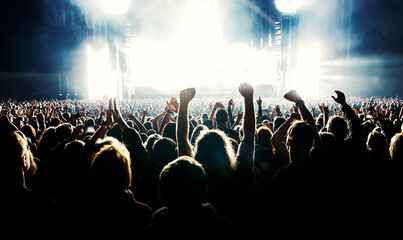 Silhouette of a happy crowd with hands up during a big rock concert.