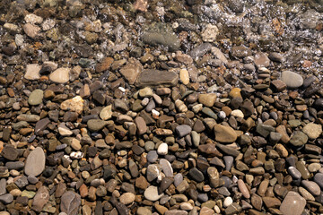 Sea pebbles and an incoming sea wave on the Black Sea coast of the Krasnodar Territory resort on a sunny day, Sochi, Russia
