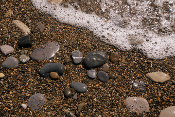 Sea pebbles and an incoming sea wave on the Black Sea coast of the Krasnodar Territory resort on a sunny day, Sochi, Russia
