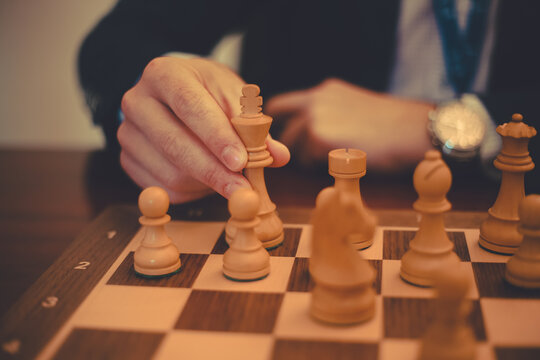 Cropped view of a man playing chess protecting his white King