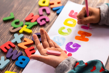 English alphabet made of square wooden tiles with the English alphabet scattered on hand. The concept of thinking development, grammar