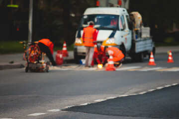 Process of making new road surface markings with a line striping machine, workers improve city infrastructure, demarcation marking of pedestrian crossing with hot melted paint on asphalt pavement