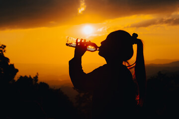 silhouette of a woman drinking water drinking water in the sunset
