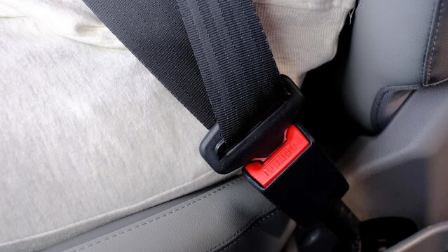 Female hand fastens the seat belt in car close-up.