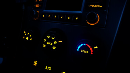 The central console of the car with the control panel of the automatic air conditioner with buttons with a bright yellow backlight