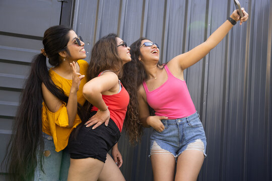 Portrait of beautiful indian women having fun party taking pictures with smart phone,Group of young girl friends in sunglasses and casual clothes laughing and celebrating all together. summer vacation