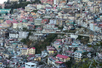 Fototapeta na wymiar Many houses on a densely populated hillside in Shimla Northern India. House in the foothills of the Himalaya mountains capital of Himachal Pradesh. Ariel view of Shimla town.
