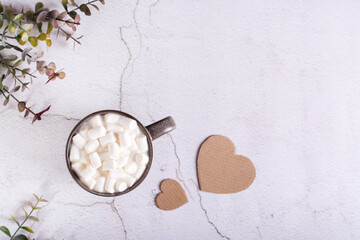Cardboard heart and a cup of cocoa with marshmallows in a mug on a gray table.  Top view