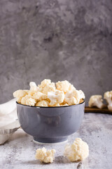 A bowl of raw cauliflower is on the table. Vitamin and vegetarian food. Vertical view