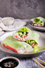 Vegetarian spring rolls with cucumber, crab sticks and lettuce on a plate. Vertical view