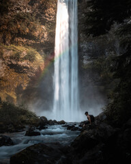 lonely man sitting by waterfall