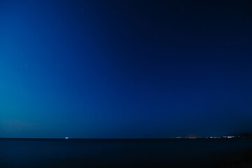 Fototapeta na wymiar Night landscape. View of the starry sky and the night city by the sea coast