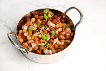 High in protein boiled black chana or chickpea salad. Chopped tomatoes, onion, chilies, and coriander mixed with boiled peanuts or Bengal gram. Weight loss meal. Served with Lemon. Copy space.