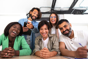 Screen view of group of multiracial coworkers looking at camera and lauging during video call in the office.