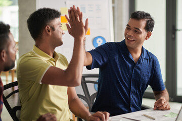 Joyful developers giving each other high five after having succeful meeting with investors