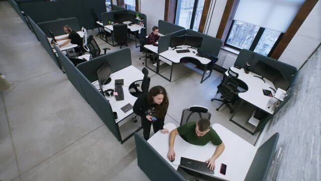 Successful people working at modern office and sitting by tables with computers. Coworkers walking corridor. Woman chats by phone and talks with male colleague. Security camera shot. Time-lapse