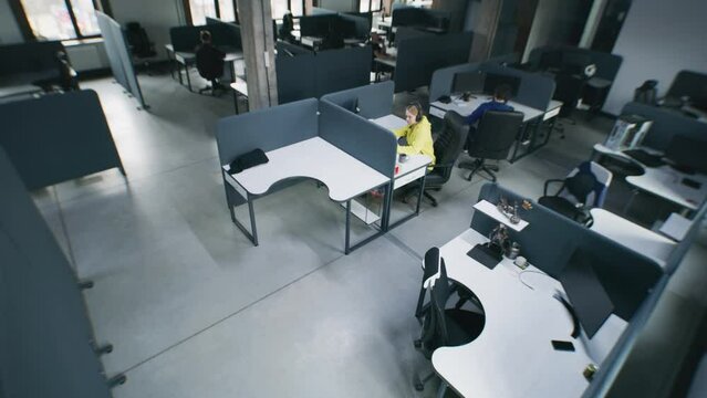 People working at office and sitting at tables with computers. Coworkers walking corridor. Woman talks with colleague, drinks coffee and chats by phone. IT company. Security camera shot. Time-lapse.