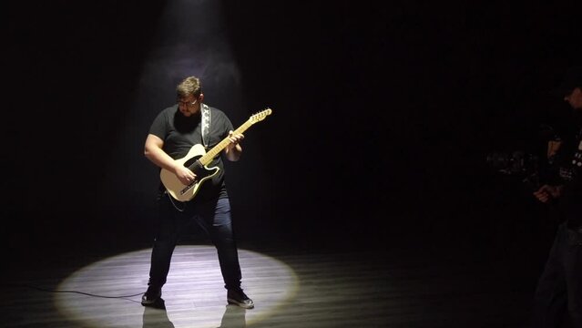 Musician playing electric guitar on festival with band. Rehearsal on the stage.