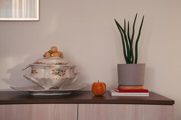 Closeup of antique bowl, apple and potted plant in bright living room