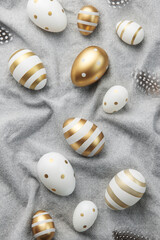 Easter eggs are painted with gold paint on a gray linen background.