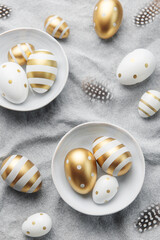 Easter eggs are painted with gold paint on a gray linen background.