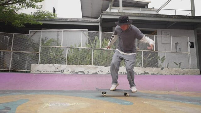 Man skateboarder skateboarding and jumping 360 flip trick on local skatepark in sunny summer. Skateboarder riding skateboard jumping flip trick.