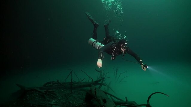 Cave diving in underwater caves of Yucatan Mexico cenotes. Divers in clean and clear underground water.