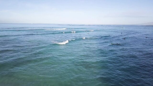 Waves aggressively crashing over surfers on waikiki beach honolulu hawaii, AERIAL DOLLY TILT DOWN