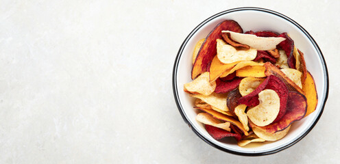 Vegetable organic chips made from potatoes, beets and carrots in a white plate for a snack, top view.