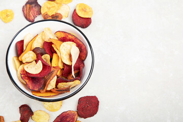 Vegetable organic chips made from potatoes, beets and carrots in a white plate for a snack, top view.