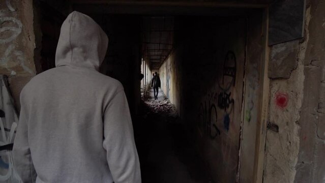 close-up of an intruder being followed by a man at night in a dark underpass.