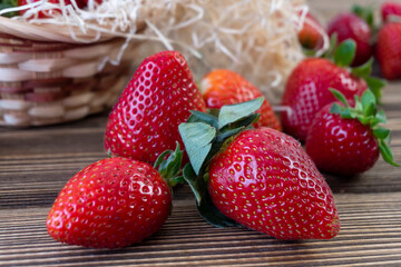 Strawberry in basket and on table on wooden background