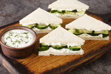Cream cheese and cucumber sandwiches closeup on the wooden board on the table. Horizontal
