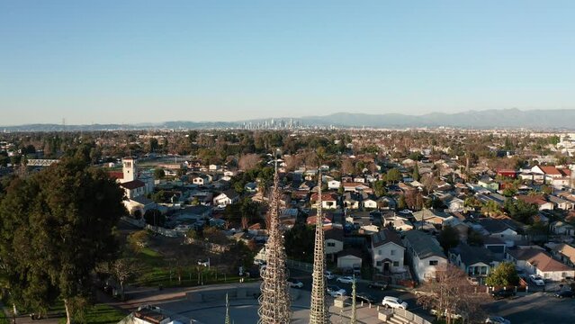 Reverse pullback aerial shot of the Watts Towers with downtown Los Angeles in the distance. 4K