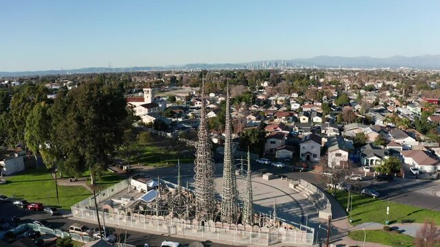 Aerial wide panning shot of the Watts Towers with downtown Los Angeles in the distance. 4K