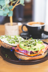 Bagels with cream, avocado, tomatoes and arugula on wooden board and table background. Healthy breakfast food.