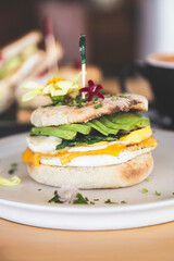 Whole wheat toasted bread with avocado, poached egg, pea sprouts and cheese over white background. Top view. Healthy diet