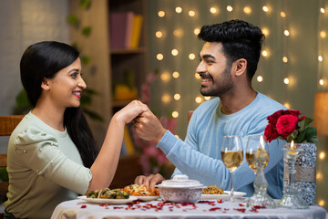 Naklejka na ściany i meble young man proposing to girlfriend by holding hands while arranging candlelight dinner - concept of love or emotion, valentine day and romantic couple